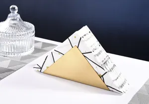 Detail shot of the modern gold triangle stainless steel napkin holder on clean white table.
