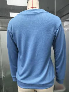 Back view detail of blue waffle knit long sleeve top, showing textured fabric closeup.