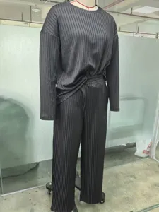 Vue détaillée du haut à manches longues plissé noir et du pantalon large en usine.