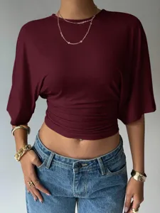 Close-up detail shot of the stylish burgundy waist-cinched short sleeve top and classic jeans.