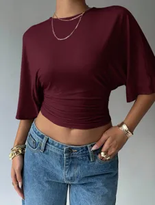 Close-up details of the chic burgundy waist-cinching short sleeve top and blue jeans.