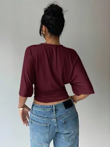 Detail view of a stylish burgundy batwing sleeve top featuring a chic cinched waist design.