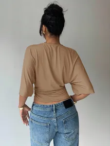 Back view detail showing the chic camel waist-cinching top paired with classic blue denim jeans.