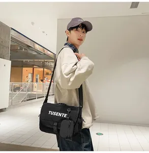 Bolso mensajero de lona negra con detalle de bolsillo pequeño, elegante bolso cruzado streetwear uso diario.