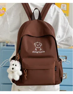 Detailed view of brown canvas student backpack with cute embroidered dog graphic and plush pendant.