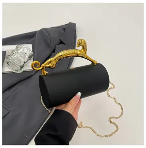 Elegant black cylinder clutch bag with luxurious gold leopard handle and chain strap for evening.