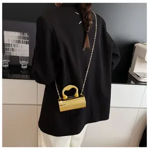 Detail shot of a sleek metallic gold cylinder crossbody bag with chain strap worn on back.