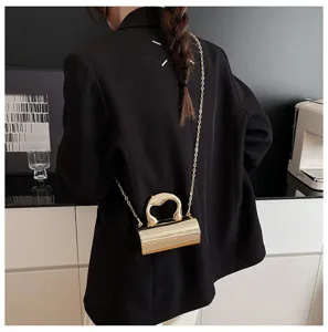 Chic metallic cylindrical shoulder bag with gold chain and unique art handle for women.