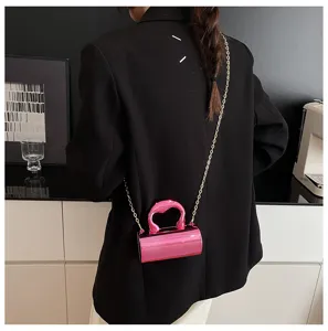Glossy pink PVC cylinder mini crossbody bag for women with gold chain and chic modern design.