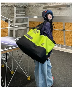 Details of the large capacity colorblock duffel bag in a trendy industrial street scene.