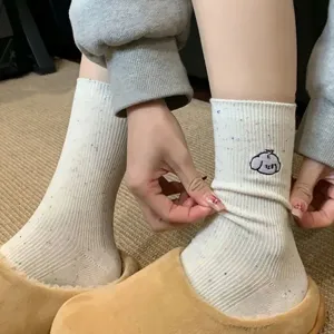 Detail shot of women's cute speckled mid-tube socks with cartoon embroidery and soft knit.