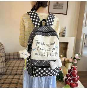 Detailansicht des niedlichen schwarz-weißen Karierten Rucksacks mit Stickerei und Plüschanhängern.
