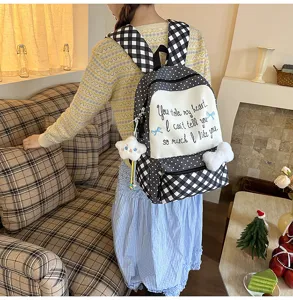 Detailansicht des süßen Karo-Rucksacks mit schwarz-weißem Muster und Plüsch-Anhänger-Zubehör.
