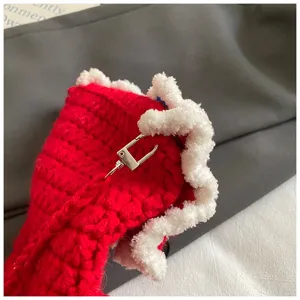 Detailed view of red knitted phone bag with plush white trim and metal clasp for winter.