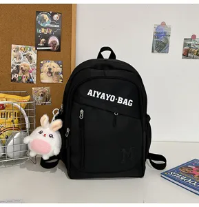 Detailansicht des schwarzen Schülerrucksacks mit weißem Buchstabenprint und süßem Plüschhasen.