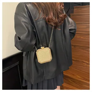 Vista dettagliata della mini borsa a tracolla dorata intrecciata con catena e chiusura chic.