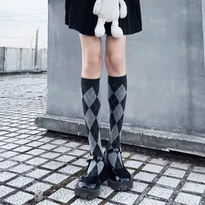 Detail shot of black and white argyle pattern knee-high college style socks paired with shoes.