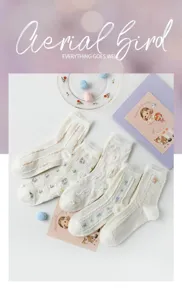 Gros plan détaillé de chaussettes blanches en coton avec broderie florale et bordure en dentelle.