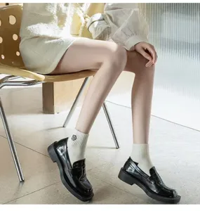 Detail view of women white short socks featuring chic black camellia embroidery design.