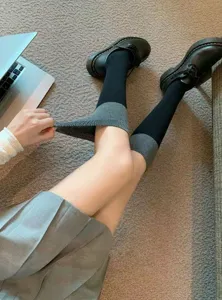 Detail shot of Japanese JK style black and gray colorblock long socks paired with shoes.
