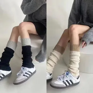 Detailopname van gebreide tweekleurige beenwarmers in grijs en crème voor de winter.