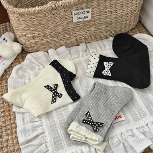 Close-up of cute cotton mid-tube socks with polka dot bows and double-layer cuffs, flat lay.