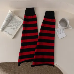 Close-up view of red and black striped knitted leg warmers, fine texture detail.