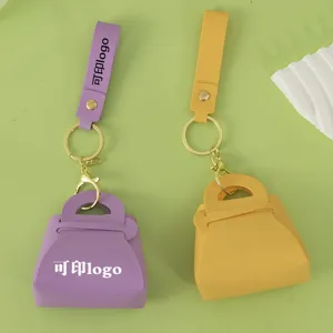 Macaron mini handbag keychain and coin purse with leather strap and metal clasp detail.
