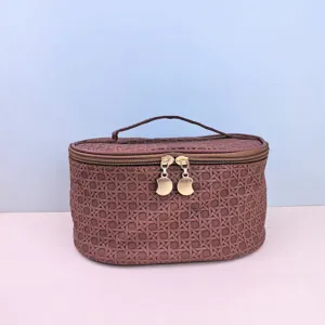 Detail view of the brown woven PU cosmetic bag, highlighting the smooth double zippers and gold pulls.