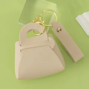 Cute leather mini handbag keychain with gold hardware, elegant bag charm detail close-up.