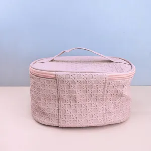 Close up detail view of the pink woven PU cosmetic bag showcasing premium texture.