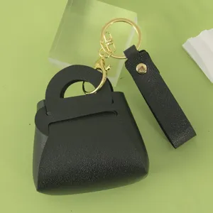 Mini black leather handbag keychain detailed view, featuring gold hardware and wrist strap.