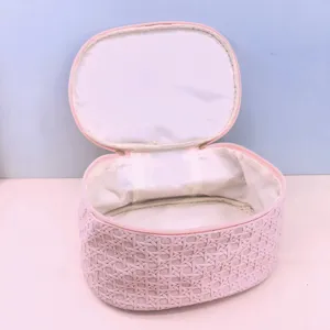 Close-up detail of the pink woven PU cosmetic bag with secure zipper and white lining