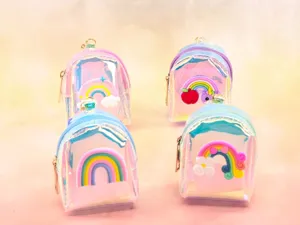 Detailed view of holographic mini backpack coin purses featuring colorful cartoon rainbow charms.