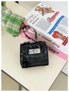 Detailed shot of a black glossy mini crocodile embossed handbag with metal turn lock and top handle.