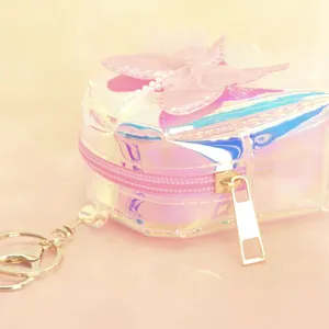 Close-up detail of iridescent holographic mini coin purse with pink bow and cute keychain.