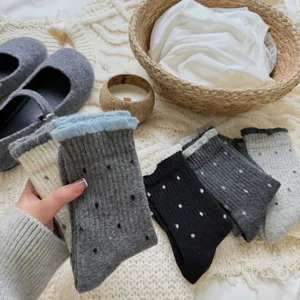 Close-up shot of cute polka dot mid-tube socks with cozy lace ruffle cuffs on knit blanket.