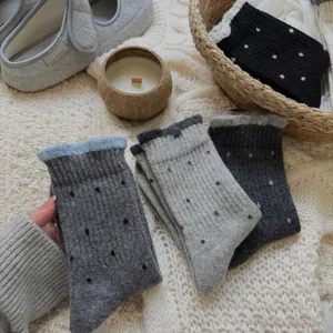 Close-up detail of cozy women autumn winter knitted polka dot socks with ruffled cuffs.