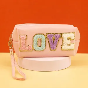 Pink cosmetic bag with colorful fuzzy LOVE letter embroidery, portable makeup storage pouch.