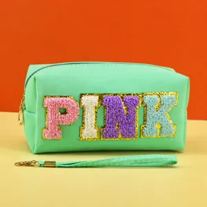 Closeup detail of mint green cosmetic pouch with cute fluffy glitter PINK letters and handle.