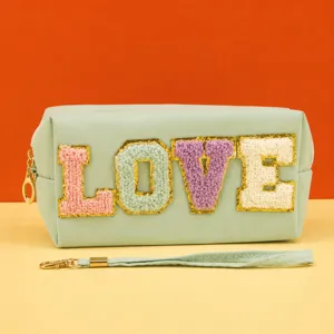 Detailed view of the mint green cosmetic bag featuring plush embroidered love letters.