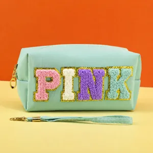 Detailed view of the light green cosmetic bag with colorful chenille letter patches and zipper.