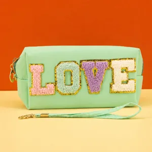 Detailed view of the mint green cosmetic bag featuring fuzzy glitter LOVE letter patch.
