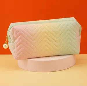 Gradient quilted cosmetic bag with chevron pattern and pearl zipper detail close-up