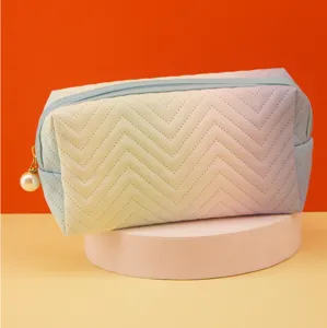 Detail shot of gradient chevron cosmetic pouch with pearl zipper pull and spacious storage design.