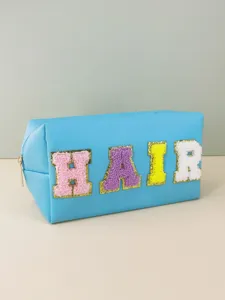 Detailed view of the blue cosmetic bag featuring colorful chenille varsity letters HAIR.