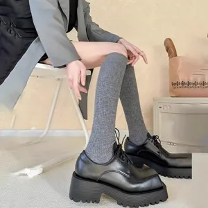 Grey ribbed knee-high socks paired with black platform shoes, stylish outfit detail shot.