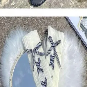 Nahaufnahme von weißen Strickstulpen mit blauen Karoschleifen für den japanischen JK-Stil.