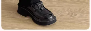 Gros plan de chaussures mocassins compensées noires brillantes avec chaussettes.