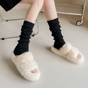 Detailed shot of cozy knitted leg warmers paired with fluffy slippers for warm winter daily wear.
